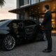 Professional chauffeur standing beside a luxury black sedan outside a premium hotel in Perth