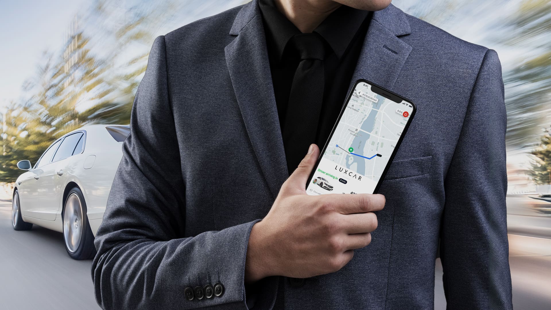 Professional chauffeur holding LuxCar booking app with luxury sedan in background for airport transfers and chauffeur services across Australia.
