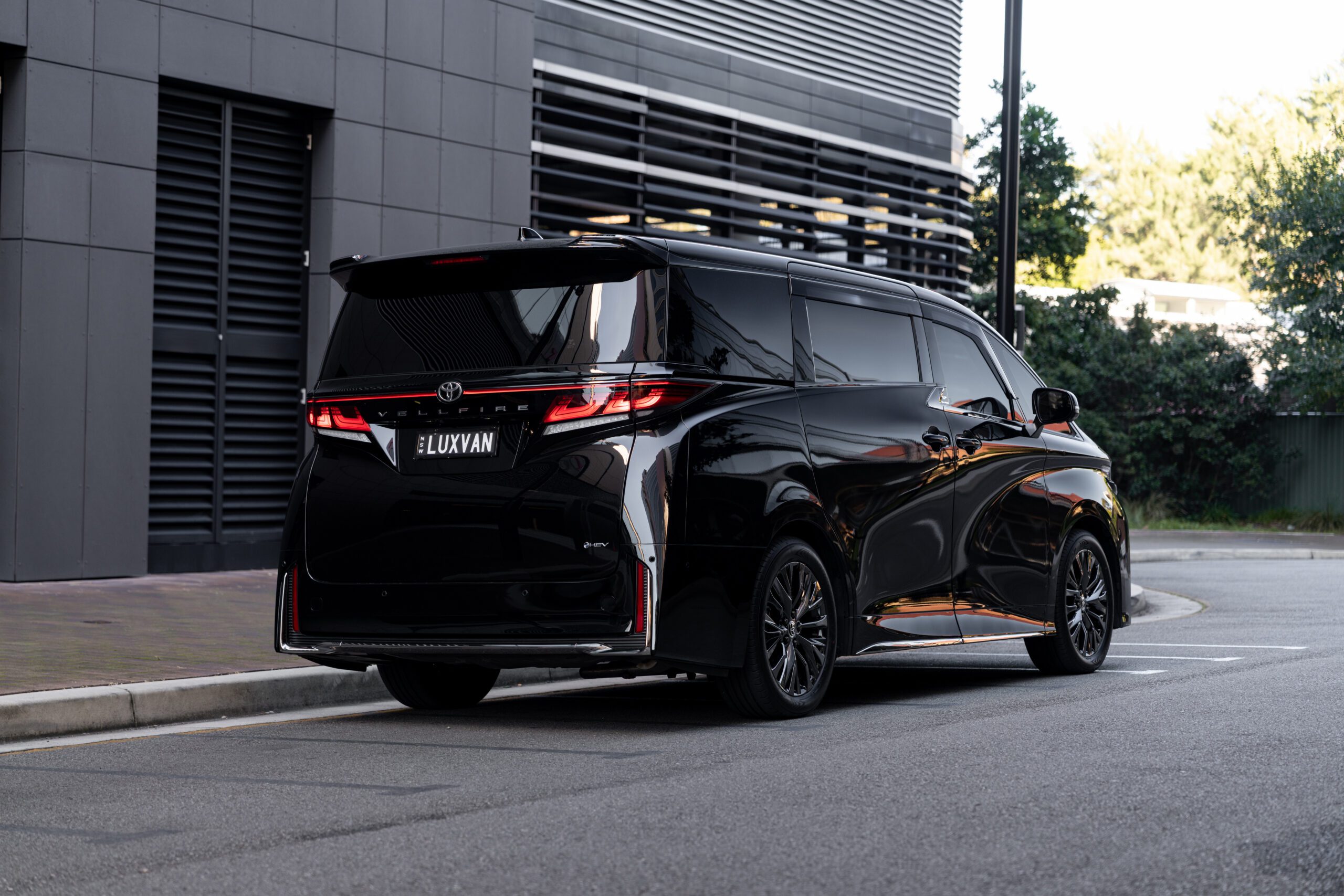 Rear three-quarter view of a luxury Toyota Vellfire chauffeur vehicle in Sydney for airport transfers, executive travel, VIP and family transportation.