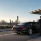 Professional chauffeur beside a luxury sedan for a Brisbane Airport to Brisbane CBD transfer