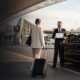 LuxCar chauffeur welcoming a passenger beside a luxury vehicle at Sydney Airport
