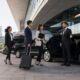 Professional chauffeur welcoming corporate conference delegates beside luxury vehicles in Sydney