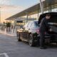 LuxCar chauffeur helping a passenger with luggage outside an Australian airport departure terminal